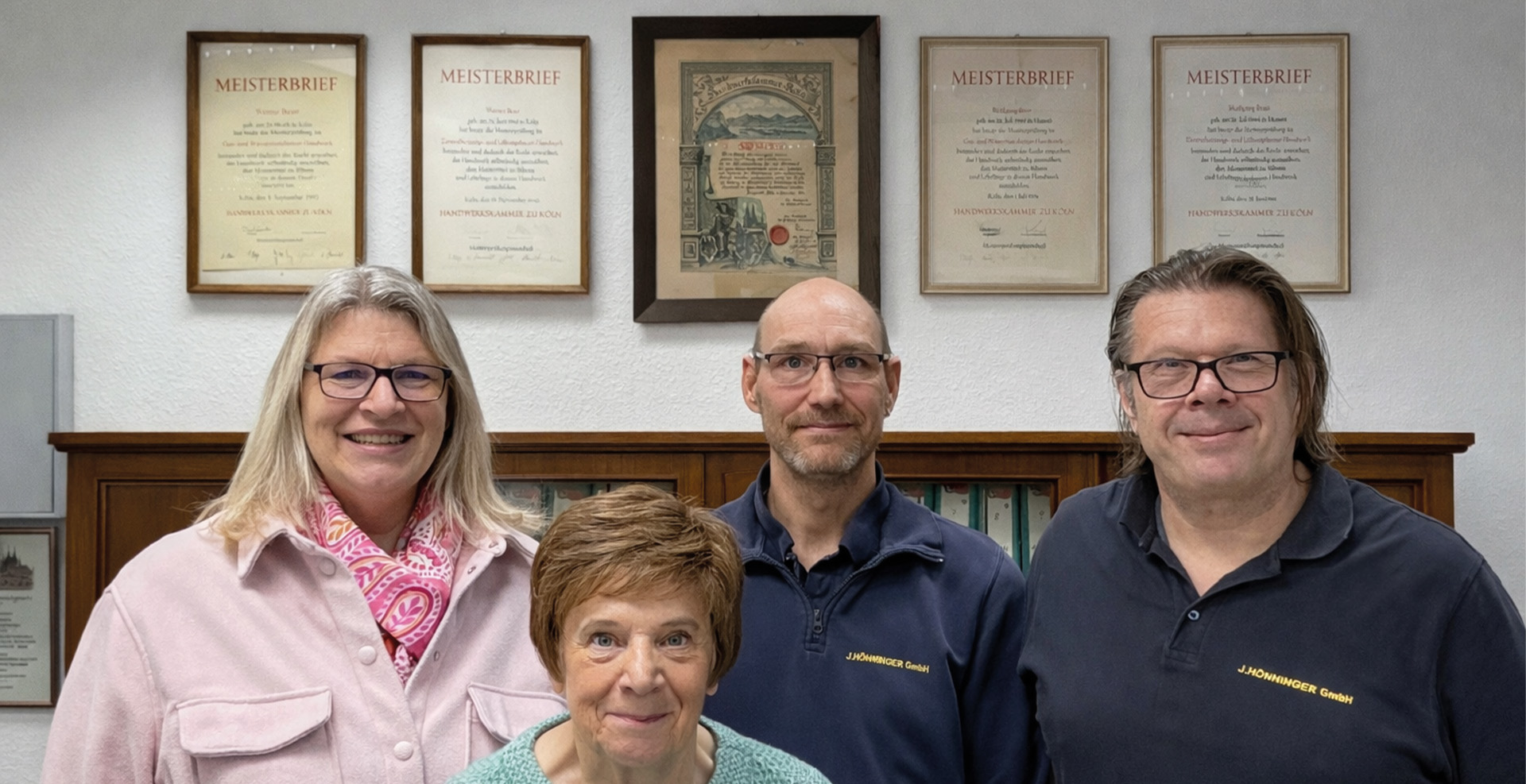 Vier Menschen posieren vor Meisterbriefen